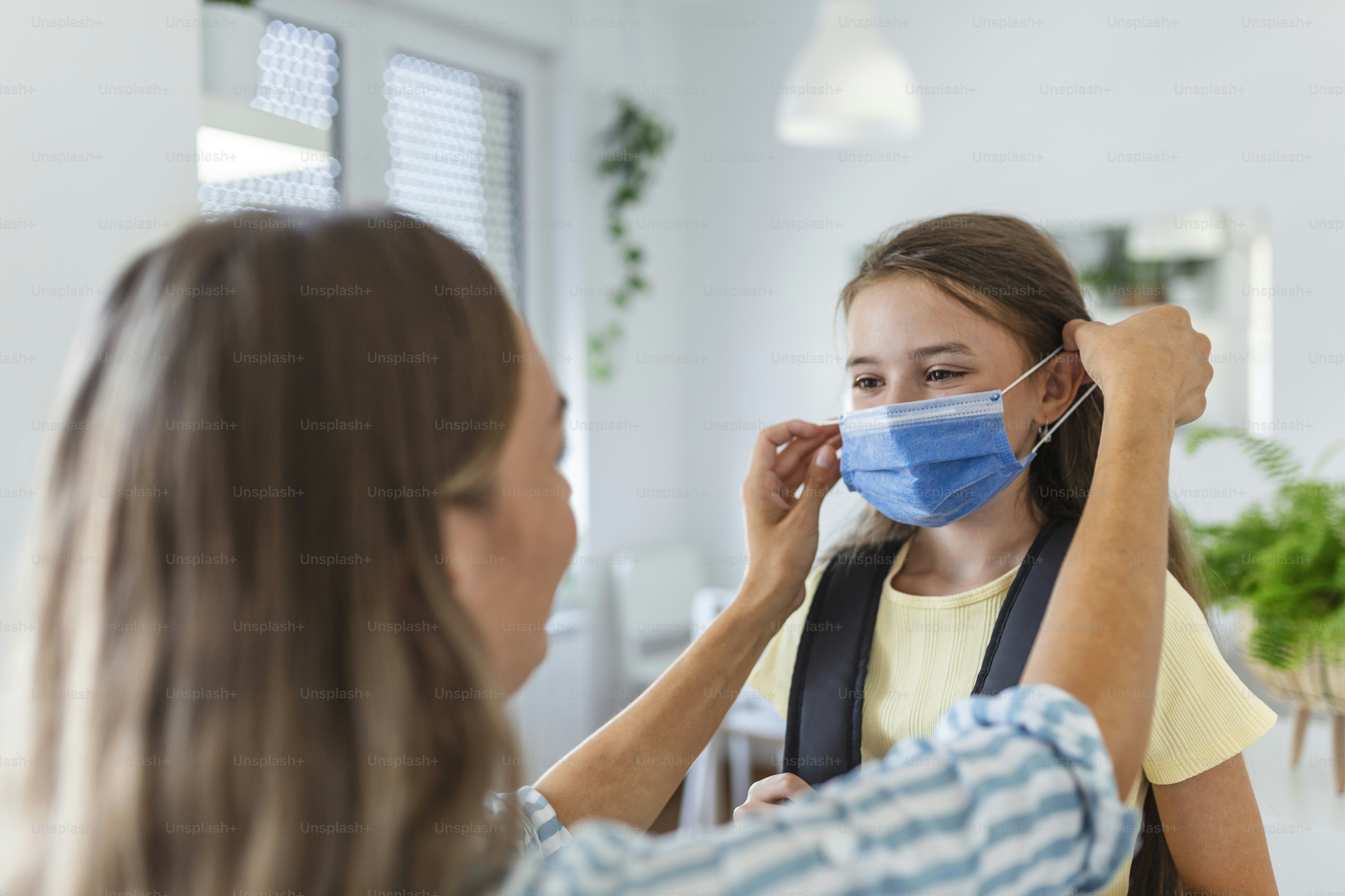 Young mother help her daughter wearing medical mask to prepare go to school. Avoiding Covid-19 or coronavirus outbreak. Back to school
