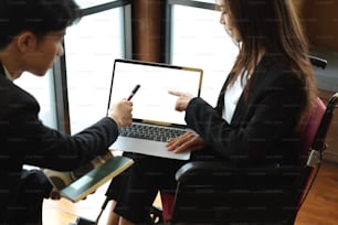 Jeunes partenaires commerciaux travaillant ensemble sur un ordinateur portable au bureau, maquette d’écran blanc d’ordinateur portable, employée en fauteuil roulant