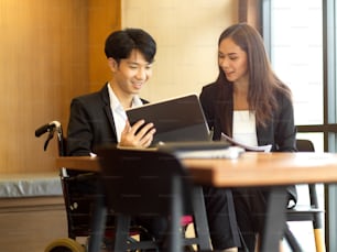 Heureux homme d’affaires et femme d’affaires parlant de leur nouveau projet au bureau. Homme d’affaires en fauteuil roulant