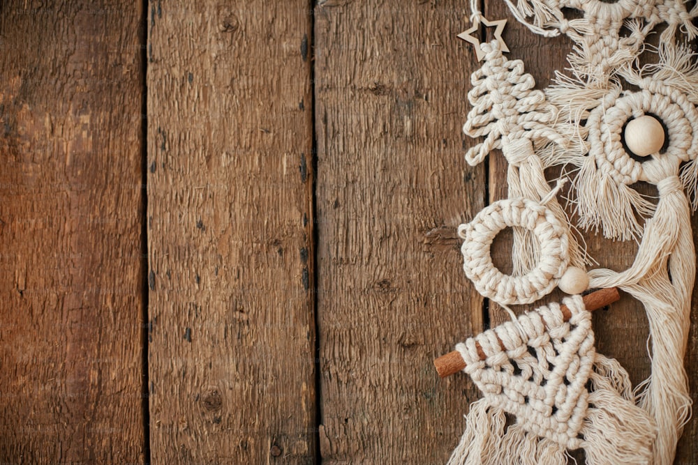 Stilvolle Weihnachtsmakramee-Ornamente grenzen an rustikale Holzflachlegungen. Handgefertigter Boho-Baumschmuck für den Weihnachtsurlaub. Frohe Weihnachten! Skandinavisches Dekor, umweltfreundliches Spielzeug. Platz für Text