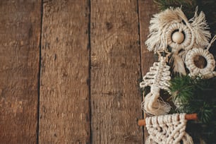Eleganti ornamenti in macramè per l'albero di Natale e rami di abete confinano con una posa piatta in legno rustico. Ornamenti boho fatti a mano per le vacanze di Natale. Arredamento scandinavo, giocattoli ecologici. Spazio per il testo