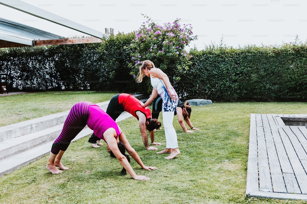 Giovani latini con istruttore che allunga gambe e braccia in classe di yoga all'aperto in America Latina