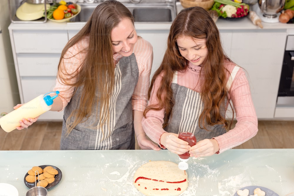In the kitchen at home, a playful mother and daughter yell while making pizza dough.