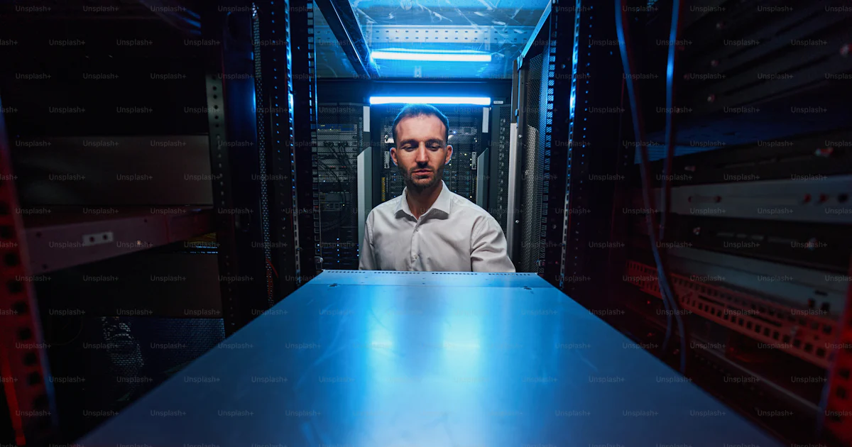 Front view of male server engineer configuring network cabinet in data ...