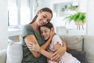 Portrait of happy young mother play hug and cuddle show love cute small preschooler daughter relaxing in living room, smiling mom and little girl child rest enjoy family weekend at home together