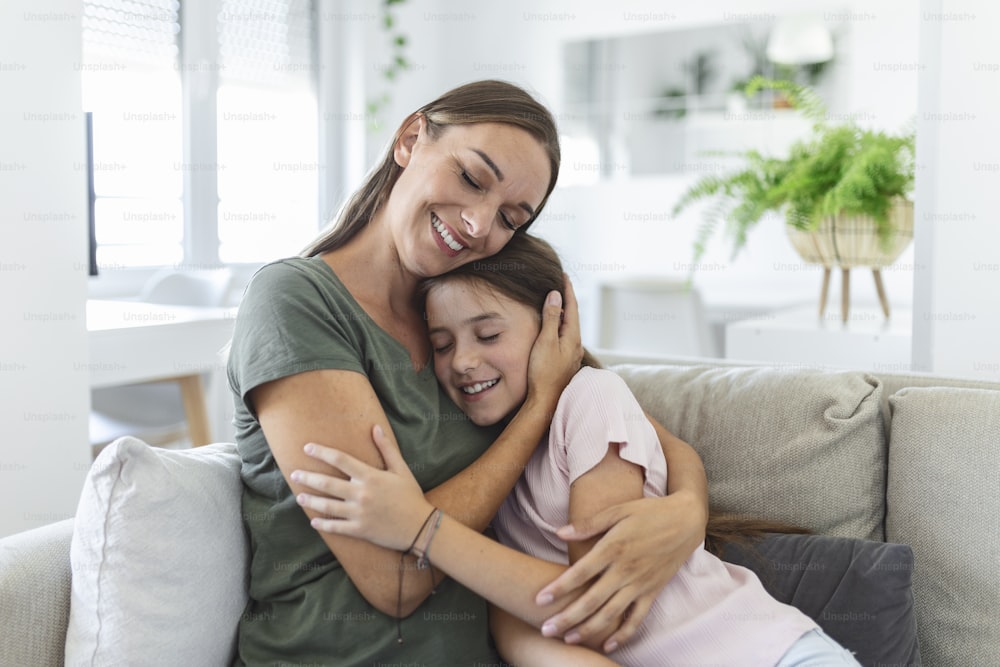 Portrait of happy young mother play hug and cuddle show love cute small preschooler daughter relaxing in living room, smiling mom and little girl child rest enjoy family weekend at home together