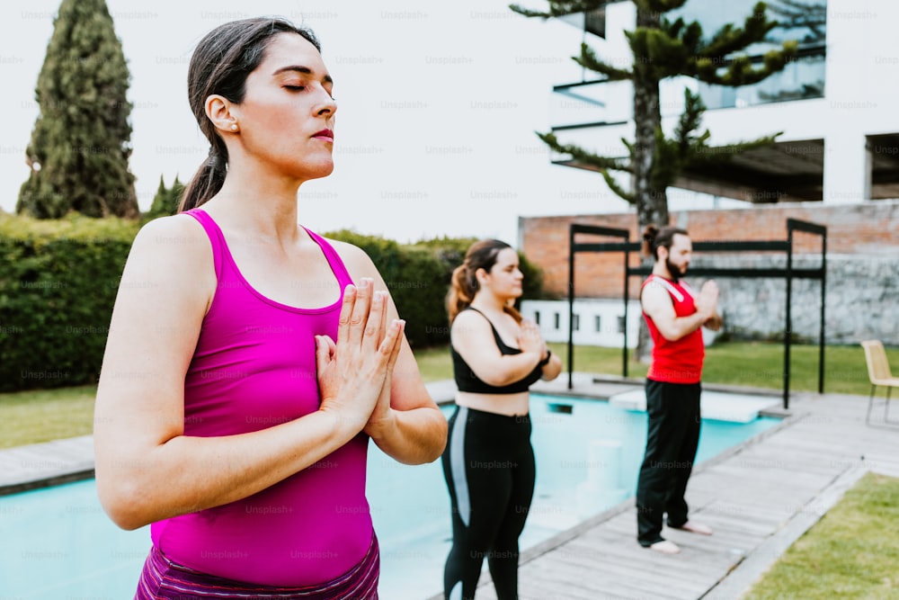 Donna ispanica di mezza età in piedi che medita con gli occhi chiusi in una sessione di yoga di gruppo in America Latina