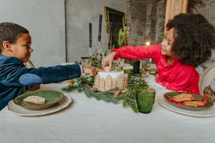 Sister and brother decorating gingerbread cake at home. Christmas time family leisure concept. Idea for diy handmade Happy New Year sweets.