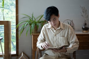 Peaceful man sitting in living room and reading book.