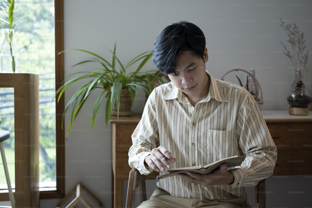 Peaceful man sitting in living room and reading book.