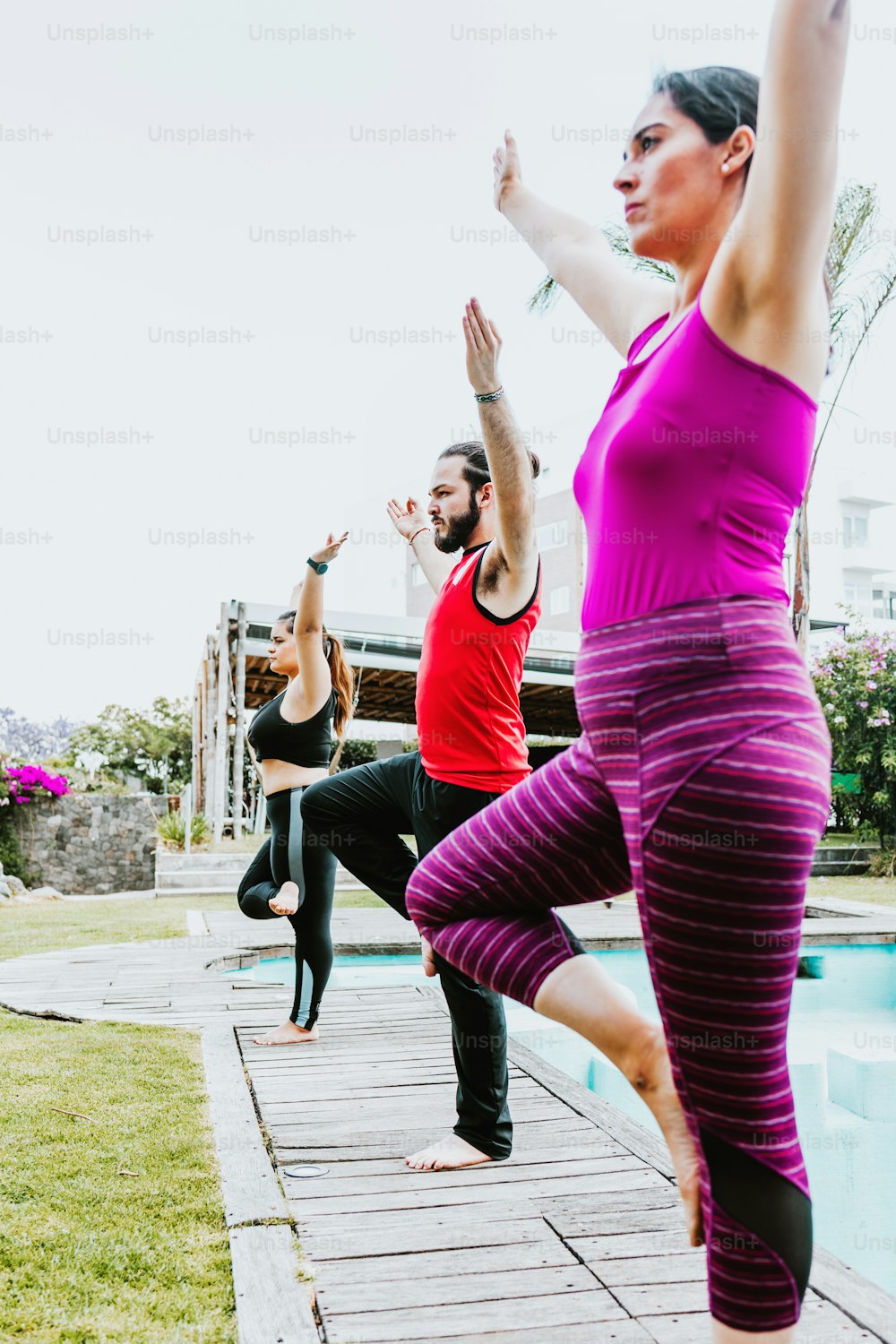 Grupo de personas latinas practicando posturas de yoga al aire libre en América Latina