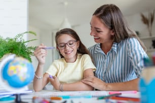 Caucasian woman looking proud at her daughter during homeschooling and doing some painting.