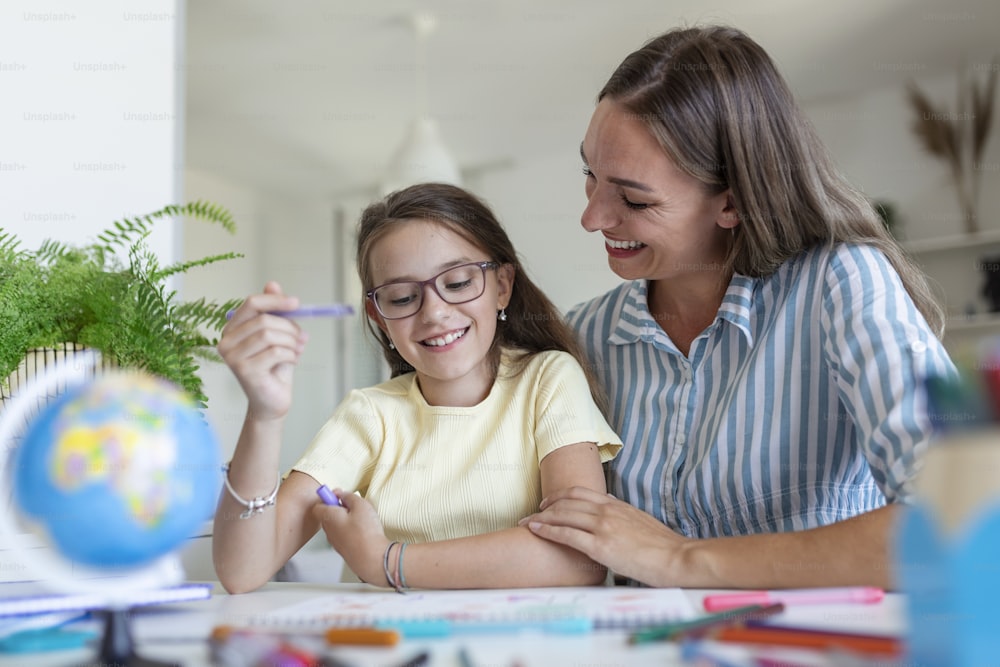 Caucasian woman looking proud at her daughter during homeschooling and doing some painting.