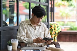 Young Asian man sitting outdoor cafe and using digital tablet.