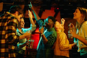 夜のバーでカラオケを歌いながら楽しんでいる若者の多民族グループ。焦点は黒人男性にあります。