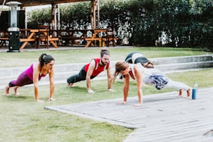 Group of young hispanic people with trainer doing push-up exercise in the garden in Latin America