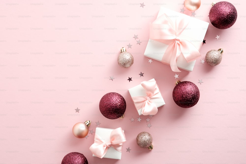 Pink Christmas background with gifts, balls, confetti. Elegant Xmas greeting card design. Flat lay, top view.