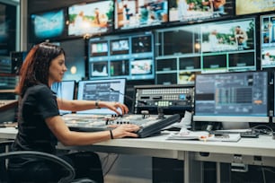 Young beautiful woman working in a broadcast control room on a tv station