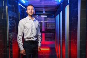 Caucasian system administrator in business casual clothes is standing near the server rack