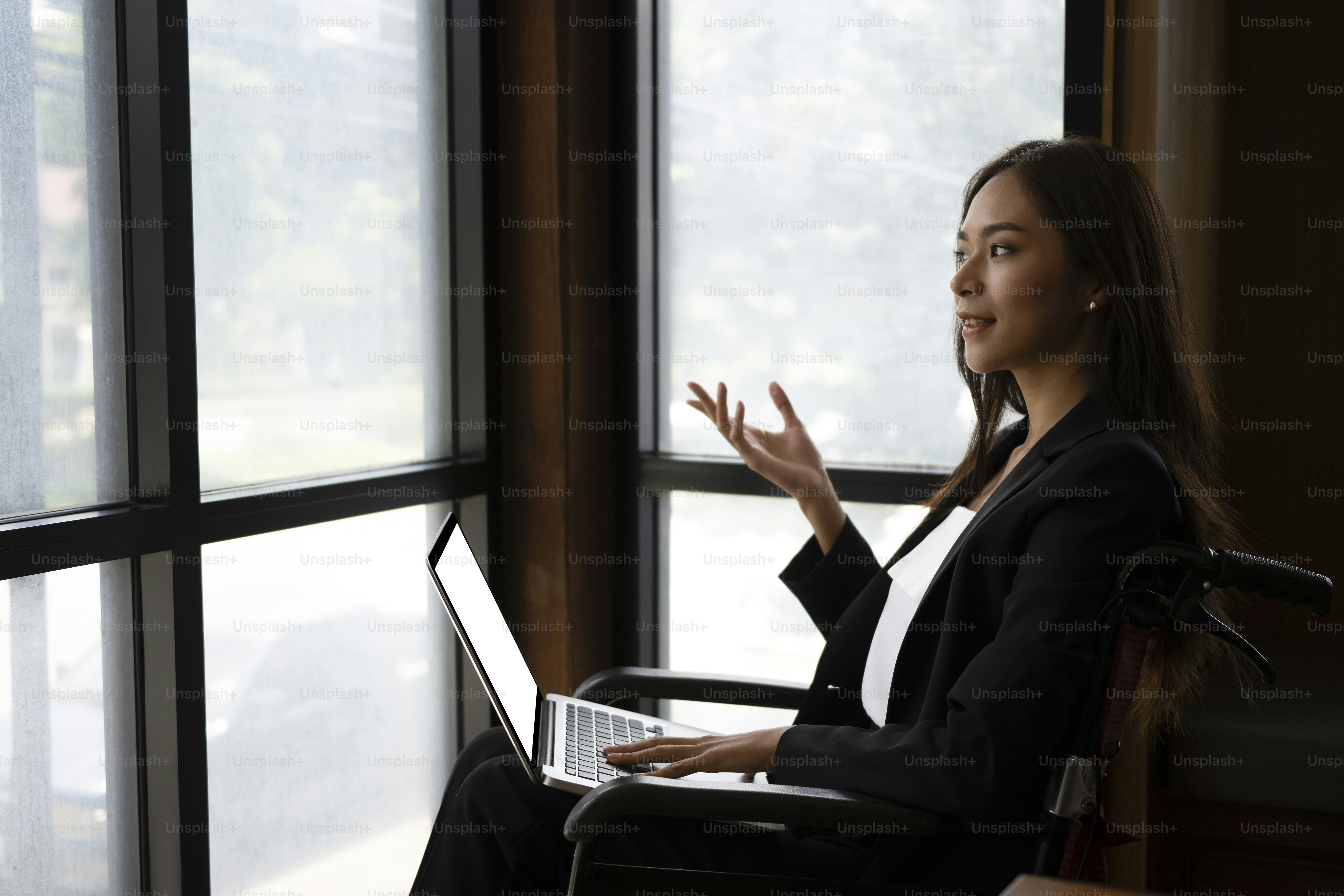 Beautiful businesswoman in wheelchair working with computer laptop in office.