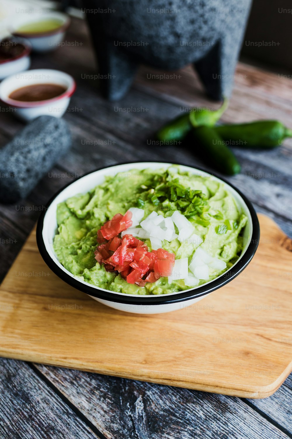 Bowl of Guacamole next to fresh ingredients on a wooden table in Mexico