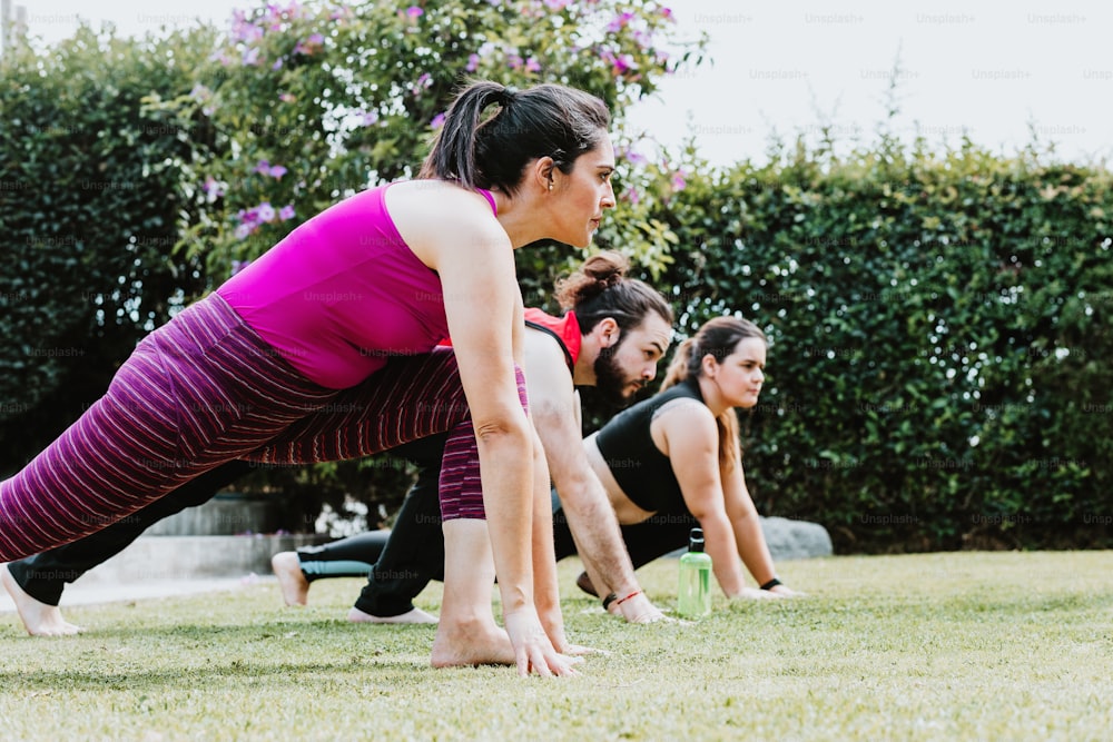 Jóvenes hispanos estirando piernas y brazos en una clase de yoga al aire libre en América Latina