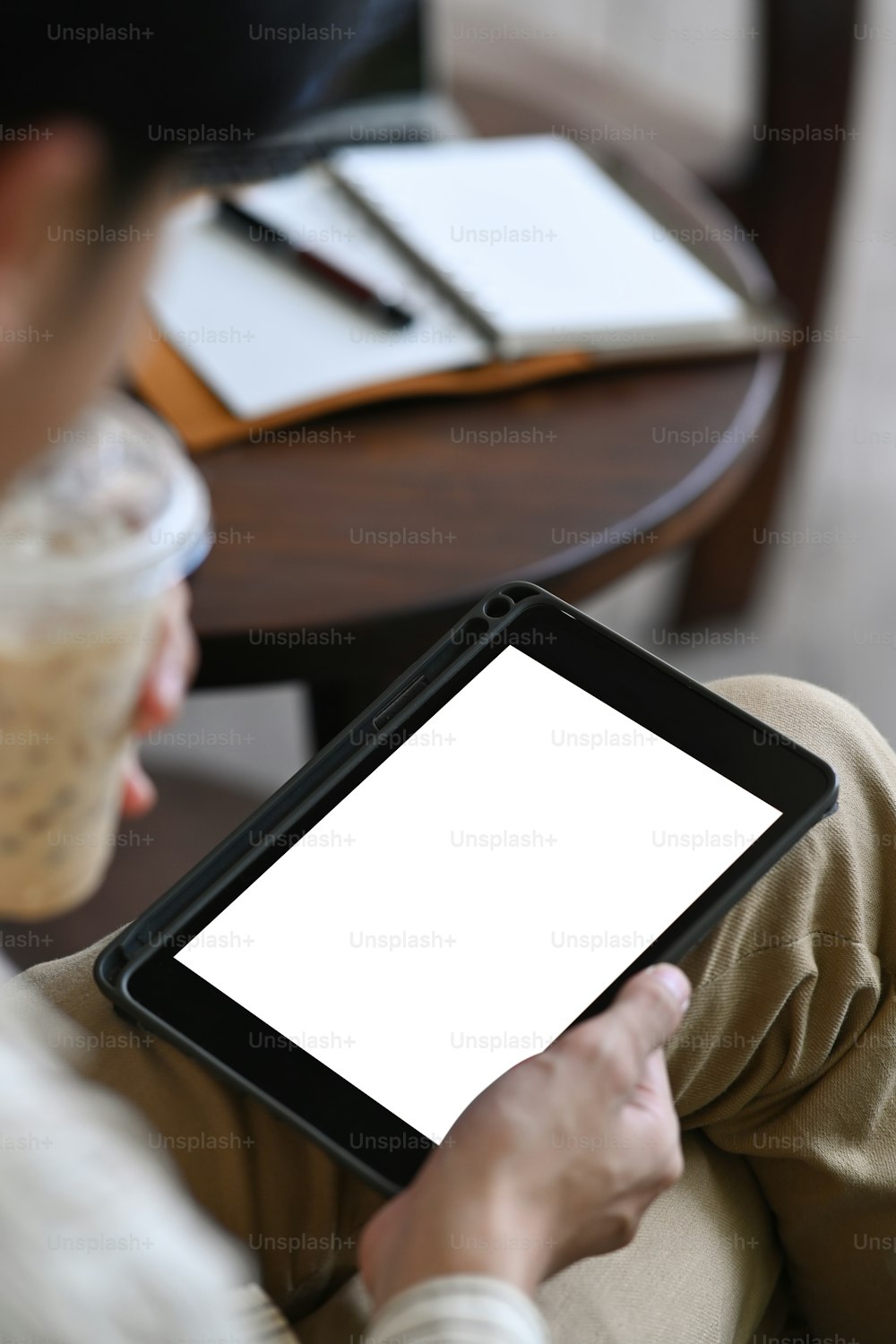 朝、コーヒーを飲みながらデジタルタブレットでニュースをチェックするビジネスマンの接写。