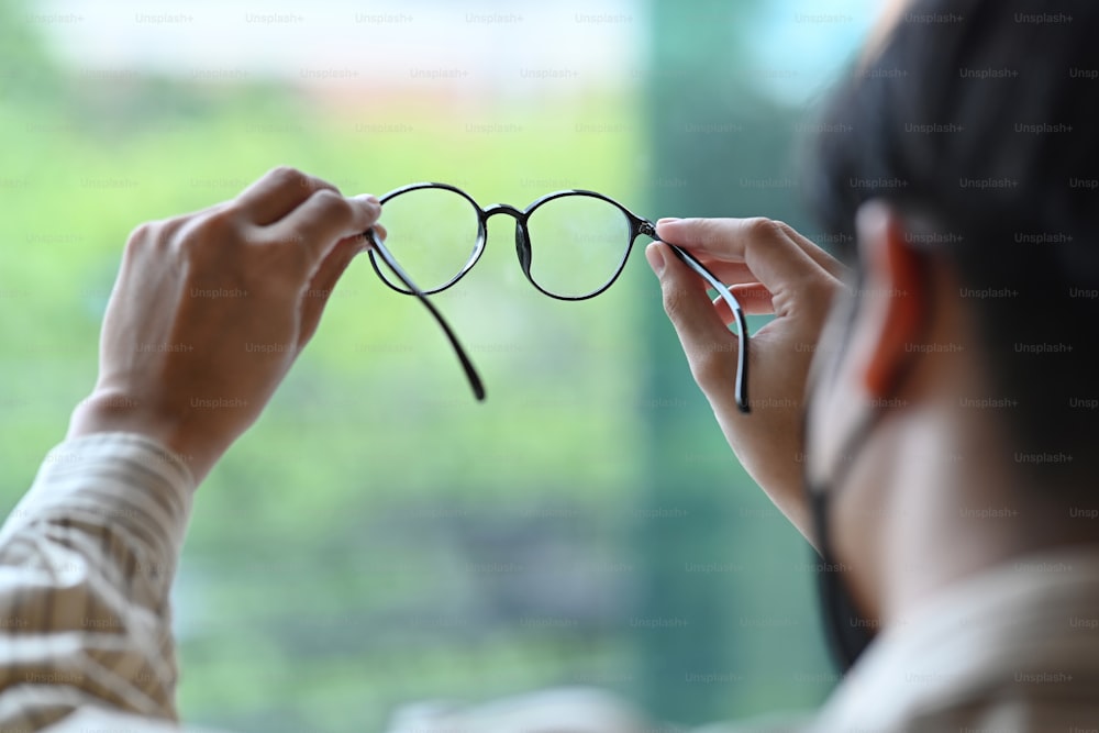 Jovem está testando um novo óculos enquanto está em pé na clínica de oftalmologia. Visão e conceito de visão.