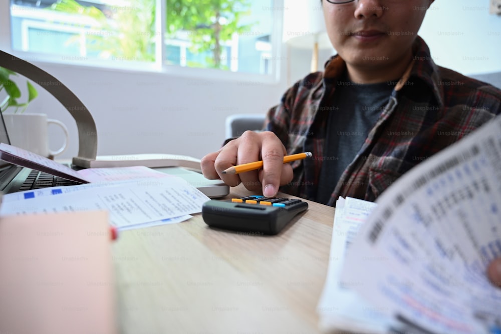 Man calculating household finances and expenses in living room.