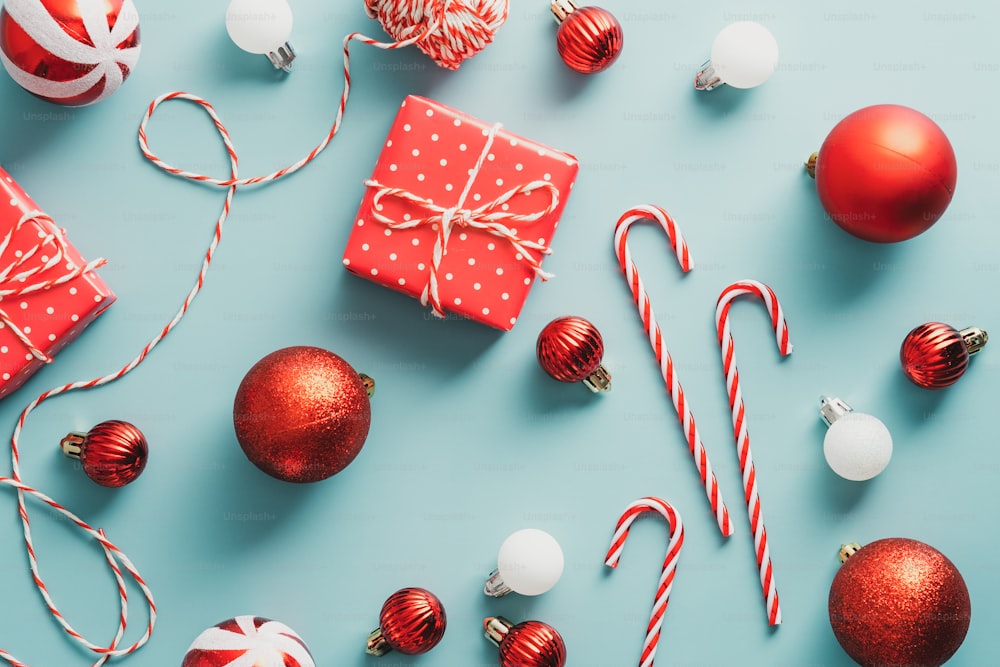 Composición plana navideña de Vintgae con cajas de regalo rojas, bolas, bastones de caramelo sobre fondo turquesa. Plano, vista superior.