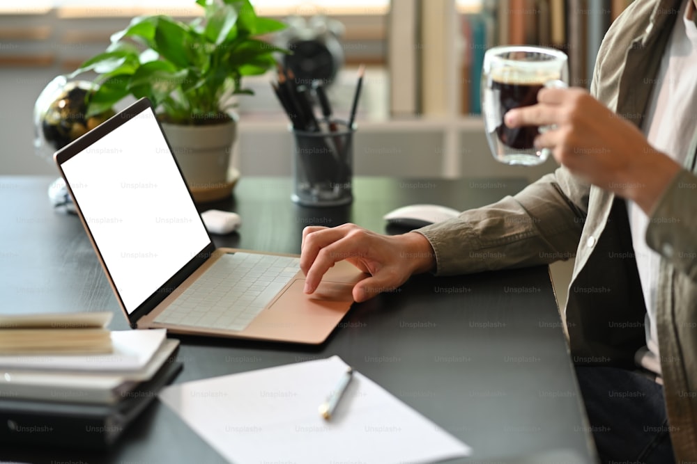 Hombre de negocios sosteniendo una taza de café y trabajando con una computadora portátil.