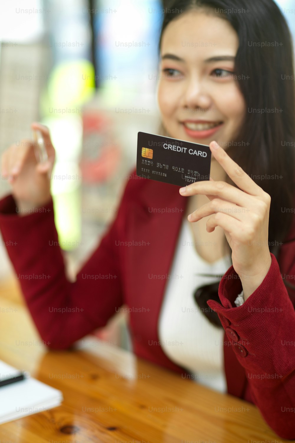 Retrato de mujer de negocios feliz con tarjeta de crédito y token de bitcoin, enfoque los objetos y fondo borroso.