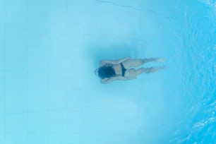 Vue de drone sur une jeune femme plongeant dans une piscine bleue