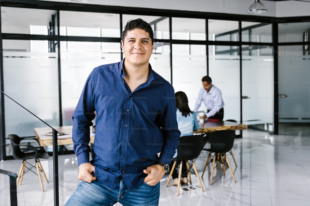 Porträt eines jungen mexikanischen Unternehmers, der mit den Händen in den Taschen im Büro in Lateinamerika steht