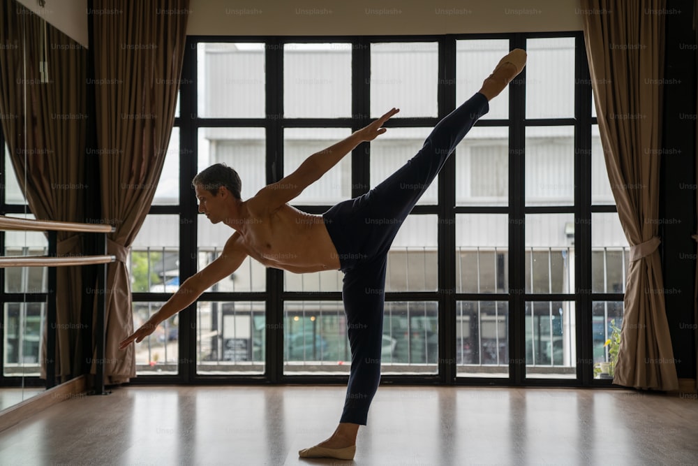 Confidence Caucasian male ballet dancer practice ballet dancing alone in studio room. Handsome man athletic dancing classic ballet showing performance body stretching and strength muscle.