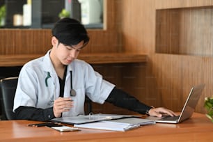 Médico inteligente em uniforme branco trabalhando em clínica médica.
