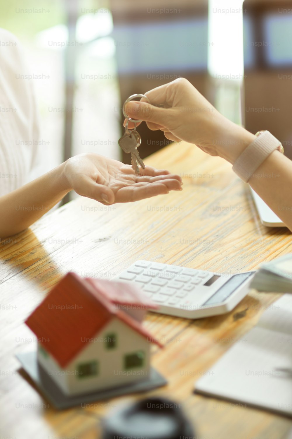 Imagem em close-up de um agente imobiliário entregando uma chave da casa a um novo inquilino depois de receber um depósito de aluguel.