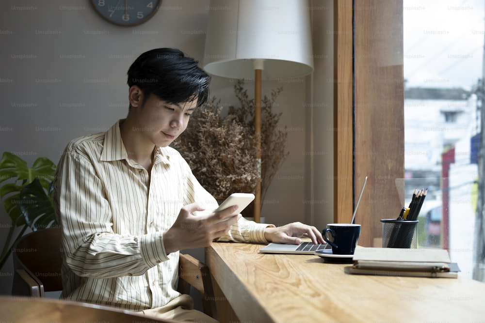 Handsome man sitting in home office and using smart phone.