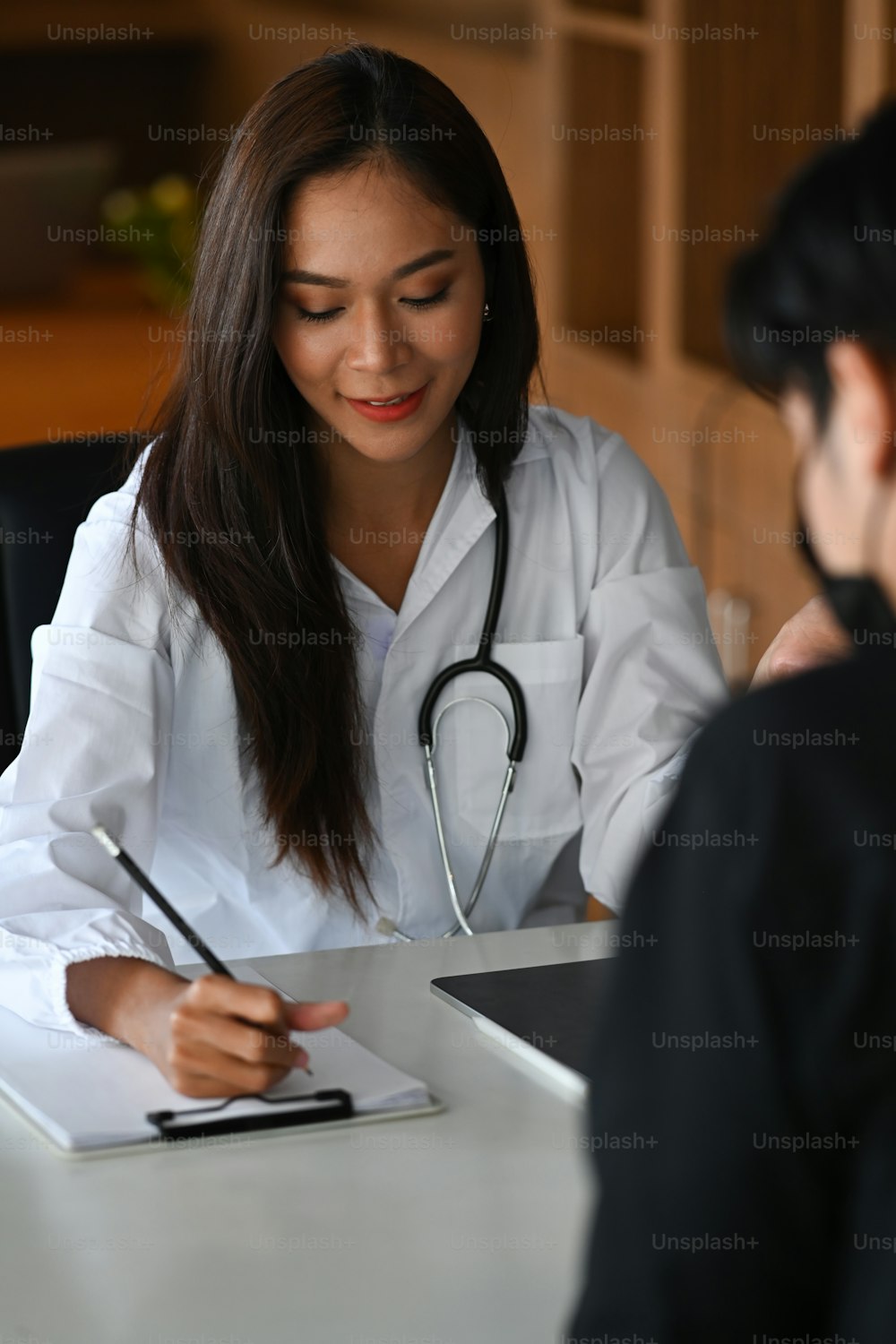 Charming female doctor giving advice to her patient in medical clinic.