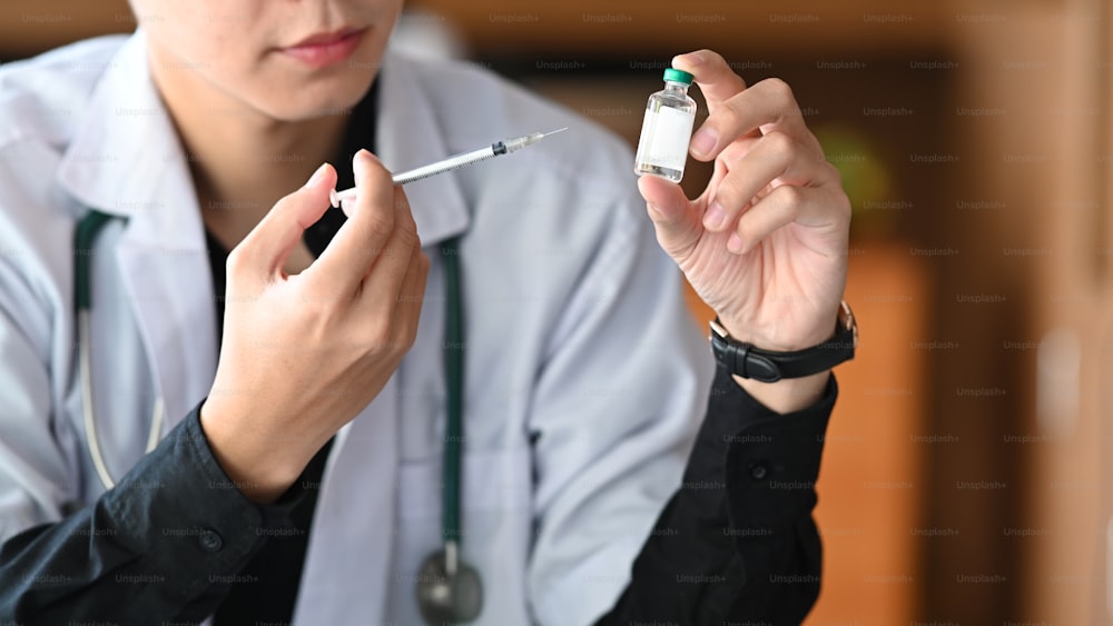 ワクチンの瓶と注射器を持つ医師。医学とヘルスケアのコンセプト。