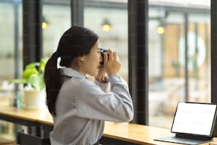 Una mujer joven feliz disfruta tomando una foto de película, sosteniendo una cámara retro vintage. Una escritora de contenido en línea toma una foto para su blog en línea.