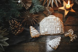 크리스마스 진저 브레드 쿠키와 양초와 장식품, 평평한 누워 소박한 나무 테이블에 장식. 설탕을 입힌 진저 브레드 하우스 만들기. 분위기 있는 분위기 있는 이미지. 즐거운 성탄절!