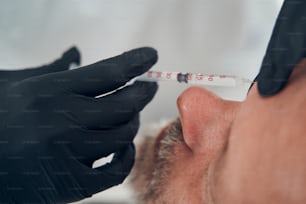 Primer plano de una persona masculina que recibe una inyección cosmética en una clínica de cosmetología