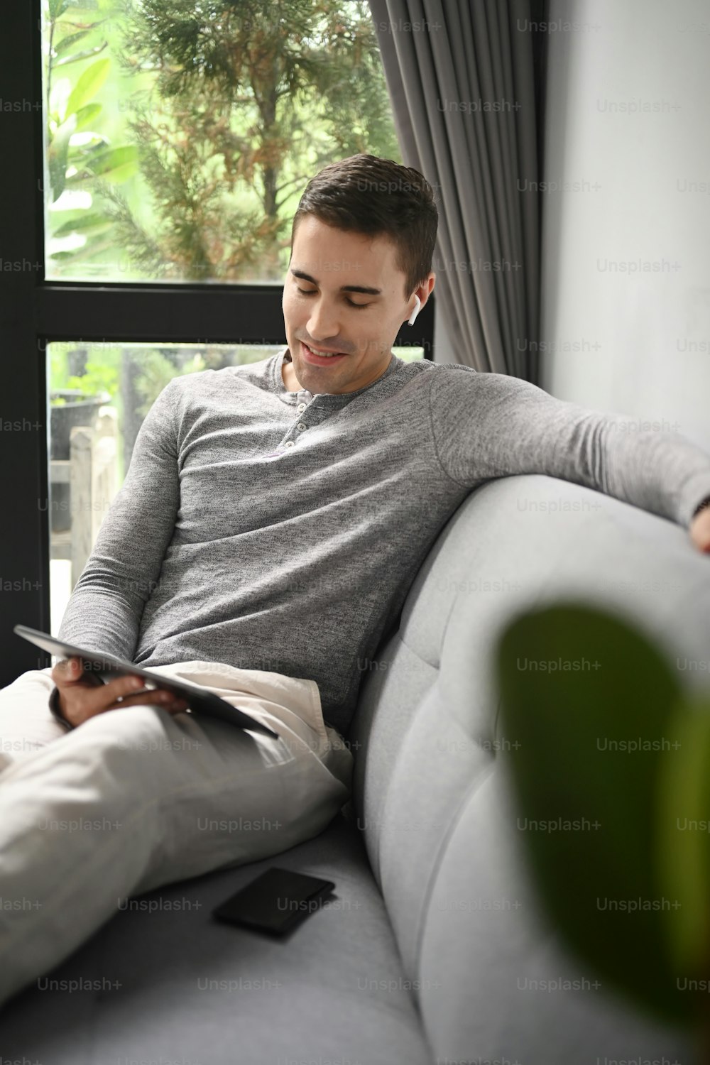 Smiling handsome man sitting in living room and using digital tablet.