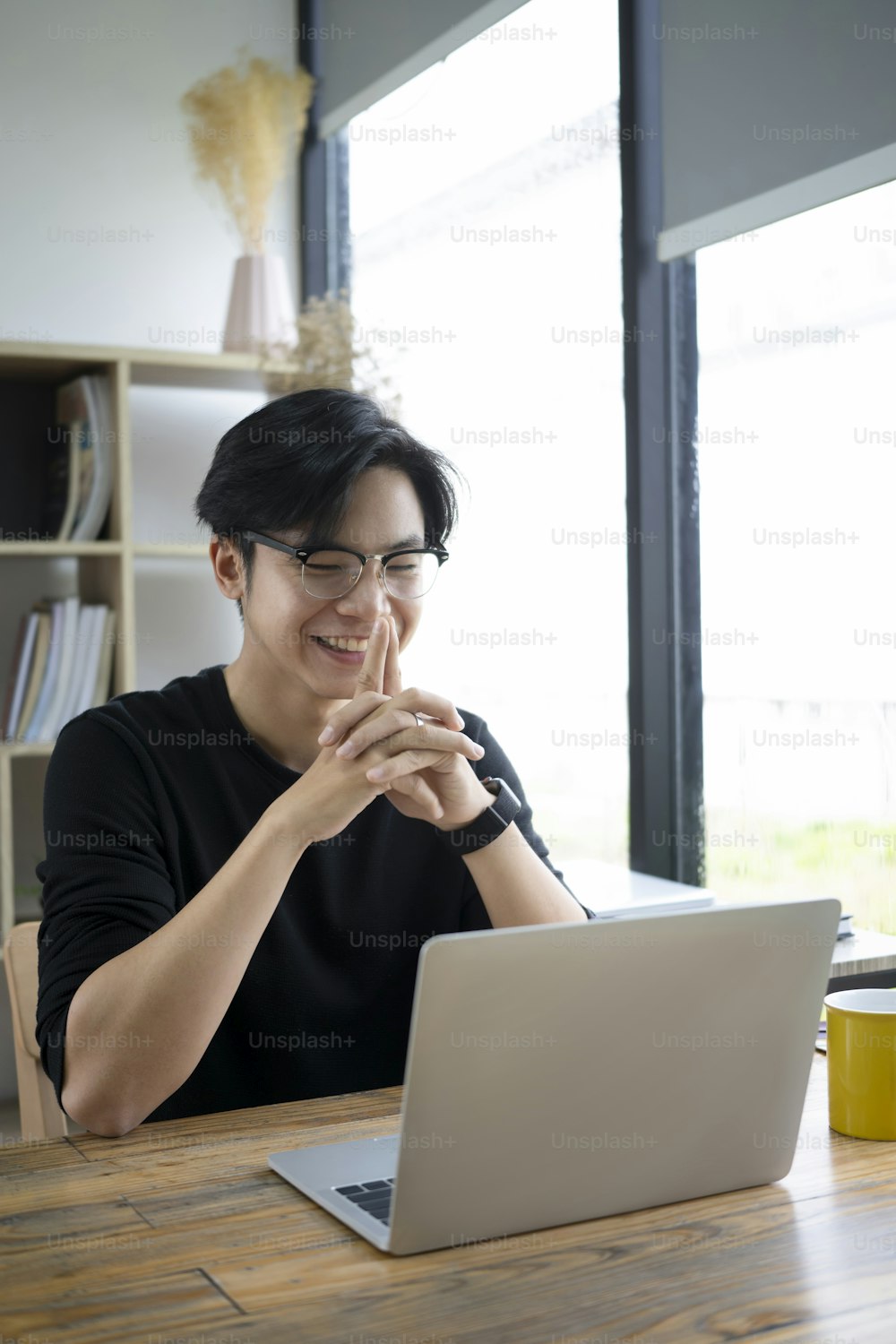 Smiling asian man having video conference with laptop computer.