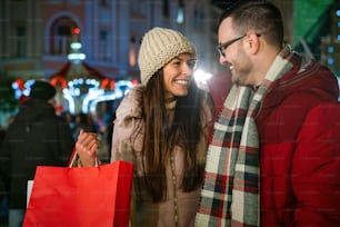 Romantic Christmas shopping. Sale and people concept. Happy young couple buying gifts for family
