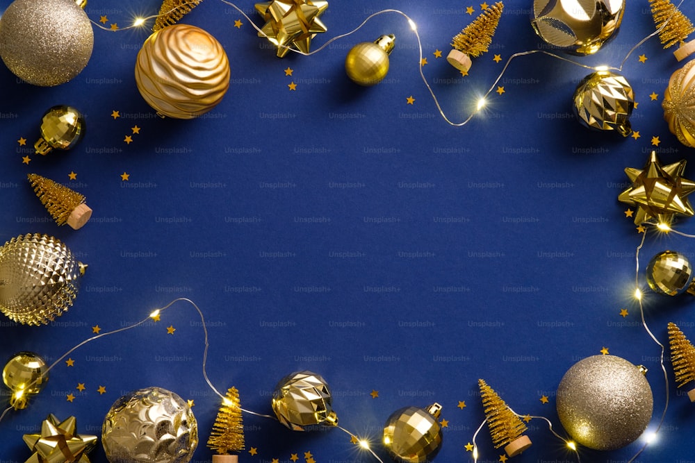 Composición navideña. Decoraciones doradas planas, bolas, oropel, luces sobre fondo azul oscuro. Marco de Navidad, diseño de banner de Año Nuevo.