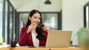 Digital money and bitcoin concept. Happy businesswoman holding bitcoin token and credit card in office, cryptocurrency.