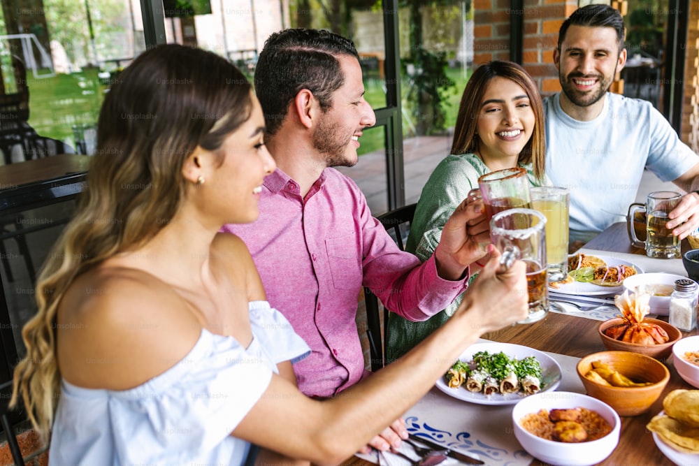 젊은 라틴 친구 모임 그룹 맥주, 미켈라다 음료와 멕시코 음식 멕시코의 레스토랑 테라스에서 토스트 만들기 라틴 아메리카