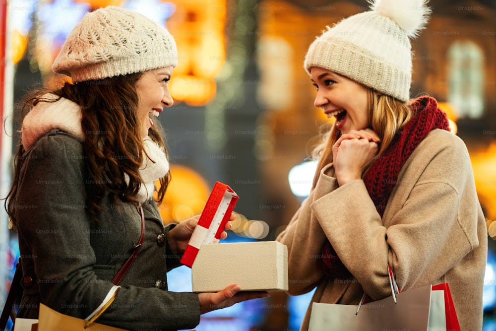 Glückliche Freundinnen, die Geschenke zu Weihnachten austauschen. Shopping Weihnachten Glück Verkauf Menschen Konzept